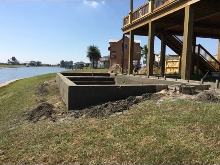 Concrete retaining wall and steps on a waterfront property with harbor water visible