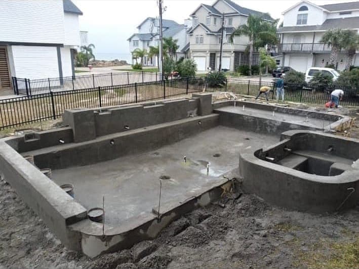 Freshly shot rectangular pool and round spa shell in a coastal beachside neighborhood