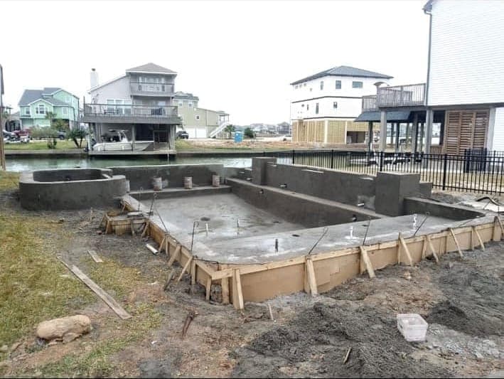 Completed gunite pool and spa shell on a waterfront lot with canal and homes in background