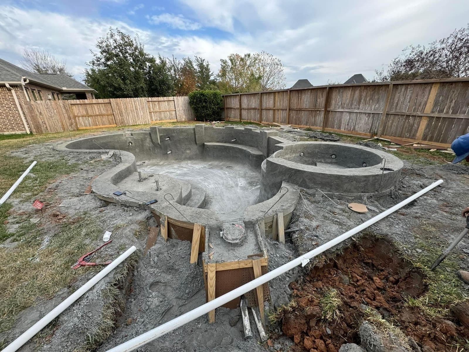 Clean freeform pool and raised spa shell freshly shot in a fenced suburban backyard