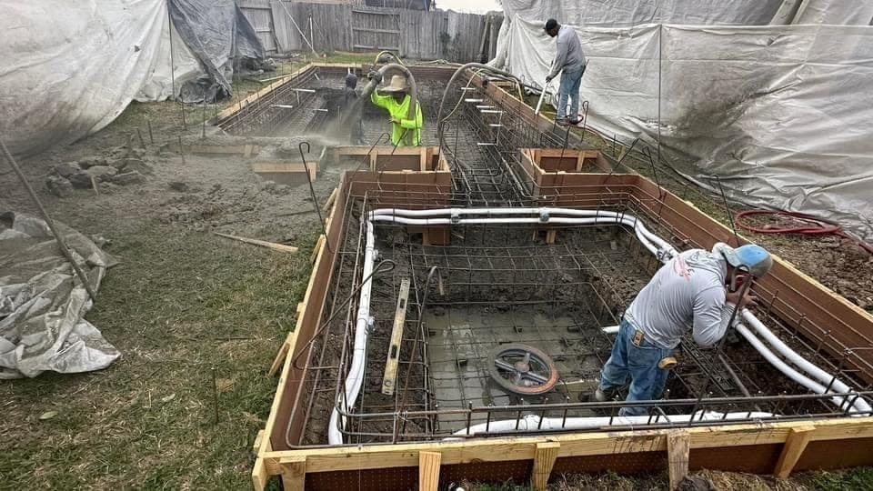 Three-man crew guniting a rectangular pool with spa, plywood forms and rebar exposed